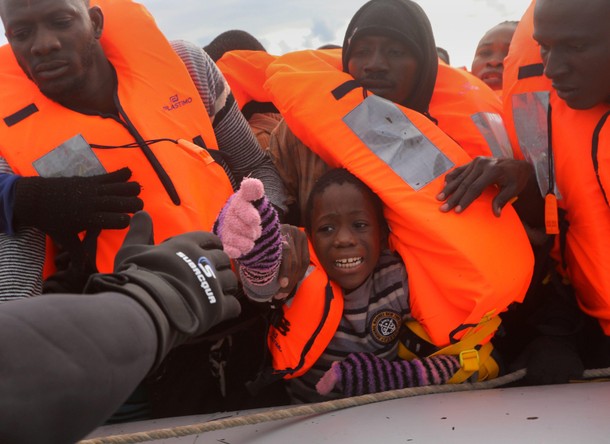 A child reacts among migrants as they try to reach a rescue craft from their overcrowded raft, while