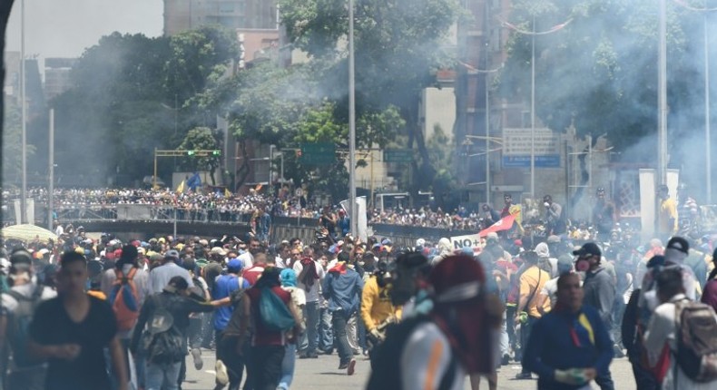 Demonstrators against Nicolas Maduro's government are seen amid a tear gas cloud during clashes with riot police in Caracas on April 8, 2017