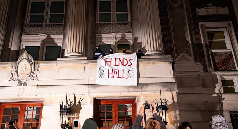 Protesters unveil a Hind's Hall banner outside of a window after occupying Hamilton Hall at Columbia in New York, New York on April 29, 2024.(Photo by Sukhmani Kaur/Sipa USA)(Sipa via AP Images)