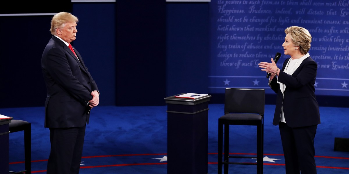 Democratic presidential nominee former Secretary of State Hillary Clinton (R) speaks as Republican presidential nominee Donald Trump looks on during the town hall debate at Washington University on October 9, 2016 in St Louis, Missouri.