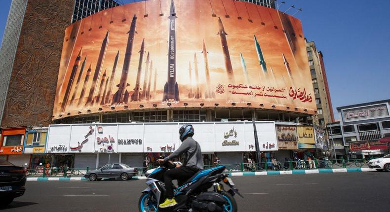 A man rides a motorbike past a billboard depicting Iranian ballistic missiles in service in Tehran on April 19, 2024.-/AFP via Getty Images