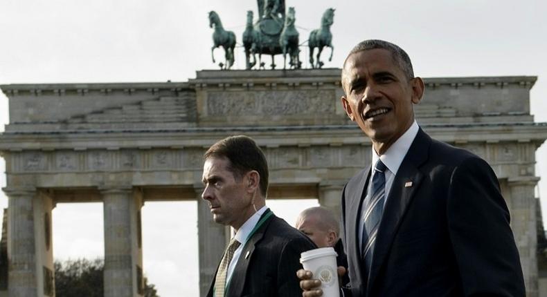 US President Barack Obama (R) passes the Brandenburg Gate in Berlin while walking from the US Embassy to the Adlon Hotel on November 17, 2016