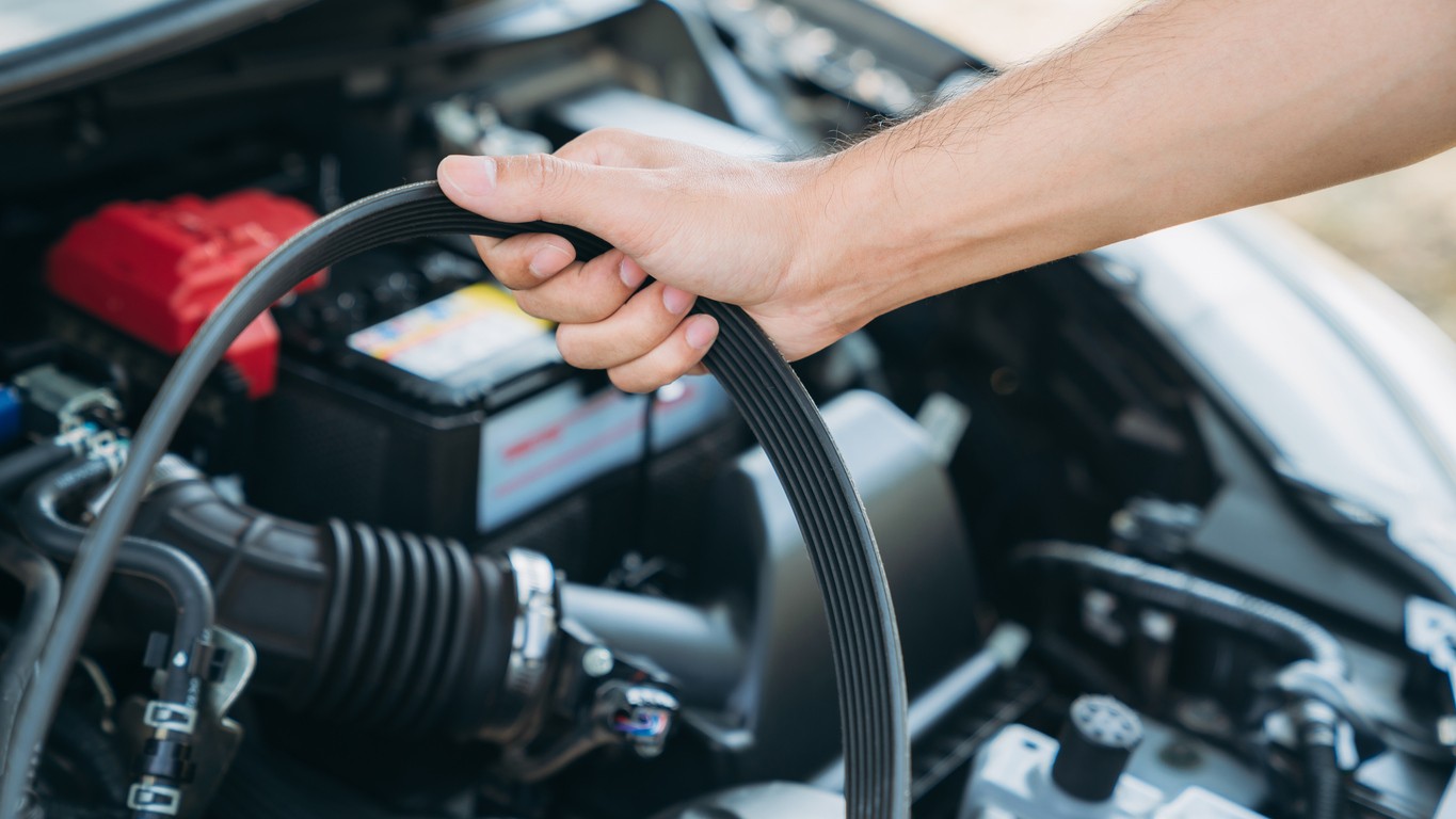 Detailný záber na mechanika, ktorý kontroluje stav rozvodovej reťaze v motore moderného vozidla.  