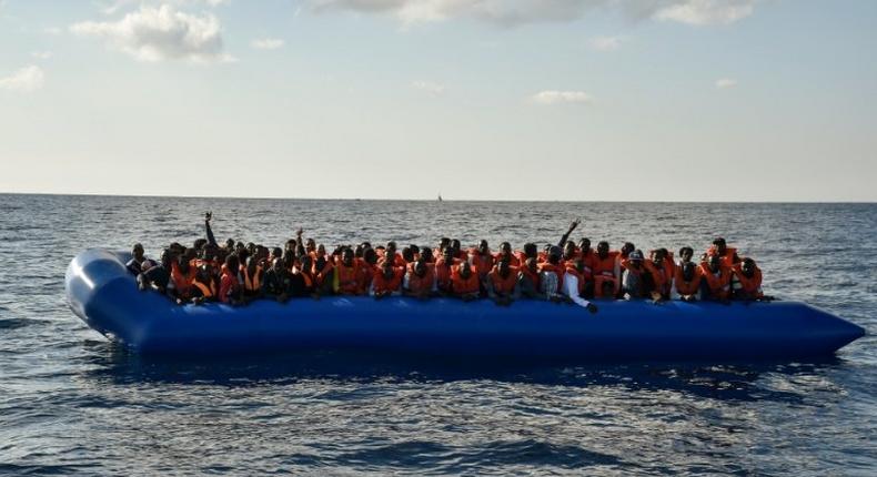 Migrants and refugees seated on a rubber boat wait to be evacuated during a rescue operation on November 4, 2016 off the Libyan coast