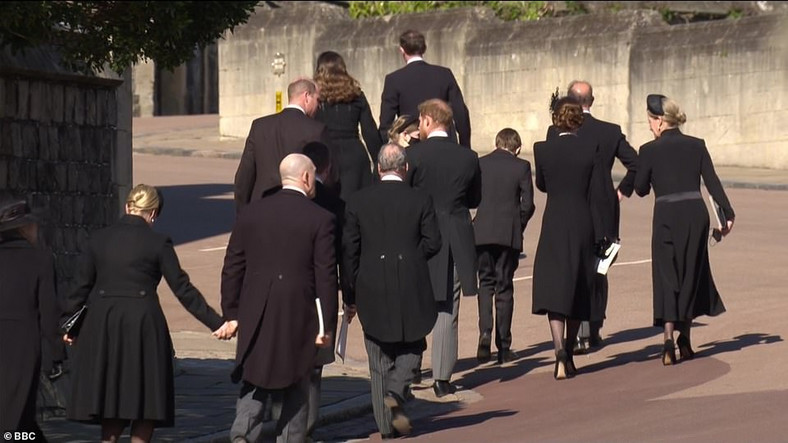 Żałobnicy w drodze do krypty. Wśród nich rozmawiający ze sobą książęta William i Harry