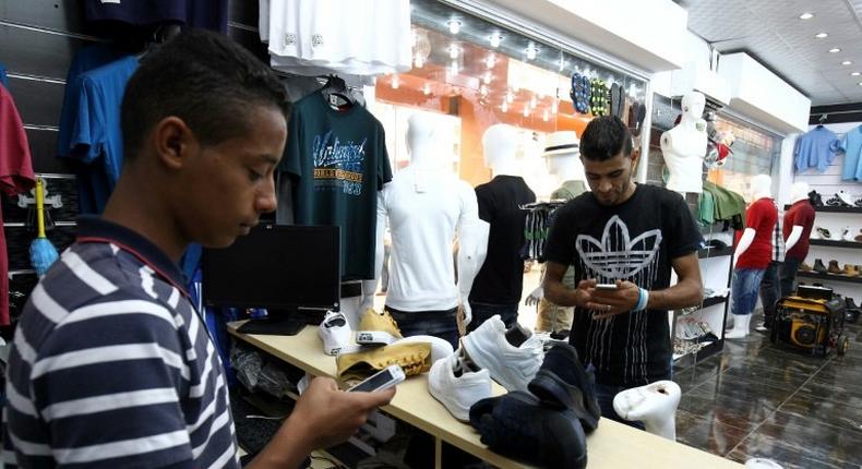 A young Libyan uses a mobile phone app to pay at a Benghazi store that accepts electronic payment systems