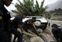 Peruvian police try to remove a car that was stuck in the mud and stones after a landslide in Chosica