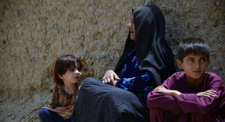 An internally-displaced Afghan woman and children who left their homes following a mass-kidnapping by suspected militants look on after arriving from the district of Shawali Kowt following in Kandahar on July 23, 2017