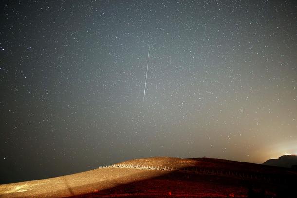 A meteor streaks across the sky in the early morning during the Perseid meteor shower in Ramon Crate