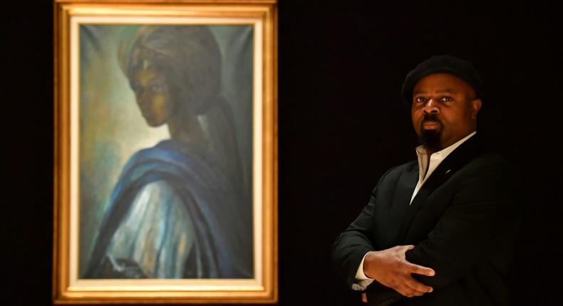 Nigerian author Ben Okri poses last year with Ben Enwonwu's 'Tutu' known as the 'African Mona Lisa'