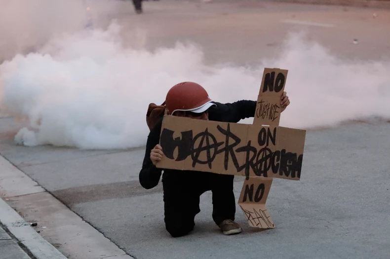 Demonstrant u Majamiju krije se iza transparenta kako bi izbegao gumene metke