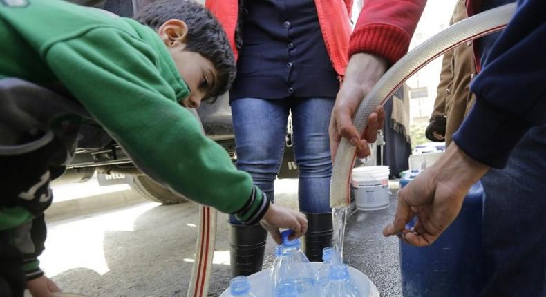 Damascus residents fill plastic containers with water provided by the Syrian Arab Red Crescent in the capital on January 10, 2017