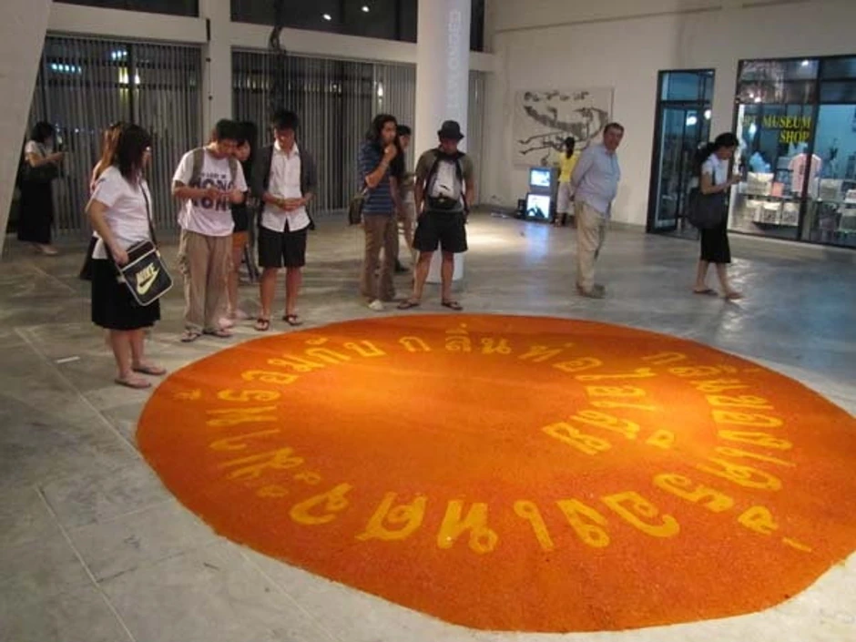 Goran Denić je na tai jeziku jakim začinima intenzivnih boja, na podu galerije ispisao rečenicu "Miris začina dolazi sa mirisom iz auspuha"