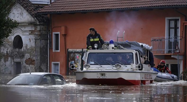 People sit in a boat of the Italian fire fighters as they help them to evacuate from their home in Moncalieri, near Turin, on November 25, 2016 because of the floods due to heavy rains