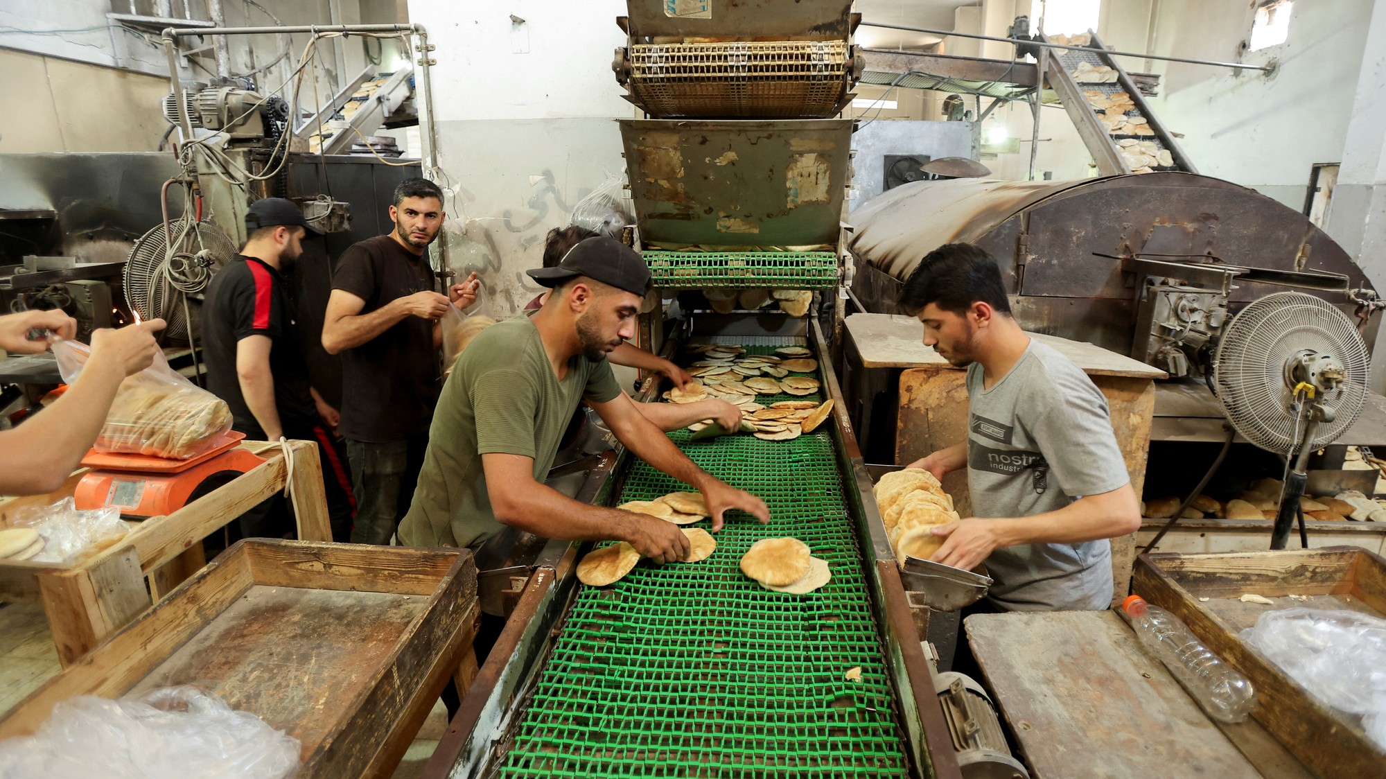 Palestínski robotníci pečú chlieb v pekárni, ktorá sa po zatvorení vrátila do prevádzky, Gaza, REUTERS/Ramadan Abed
