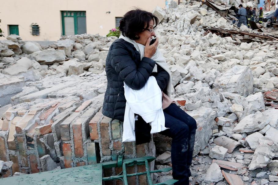 A woman sits amongst rubble following a quake in Amatrice