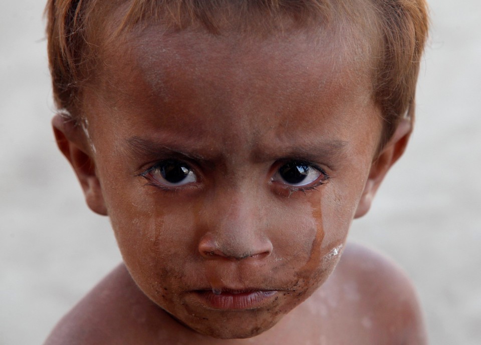 Two-year-old Imam Bux, who has been displaced by flooding, cries outside his family's tent while taking refuge in a relief camp for flood victims in Kakar village