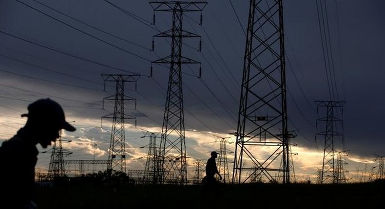FILE PHOTO: Men walk past electricity pylons as they return from work in Orlando, Soweto township, South Africa March 18, 2019. (USNews)