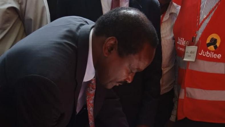 Wiper party leader Kalonzo Musyoka signs the visitor's book at a Jubilee party stand during the  People's Democratic Festival (Twitter)