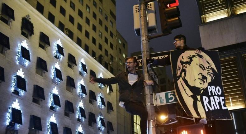 Protestors shout slogans from a lampost during a demonstration across from Trump Tower in New York