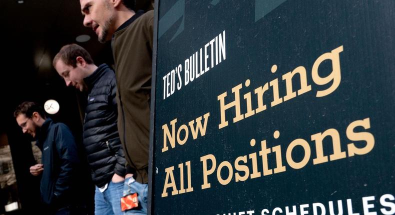 Pedestrians walk past a Now Hiring sign in Arlington, Virginia, on March 16, 2022.Stefani Reynolds/AFP/Getty Images