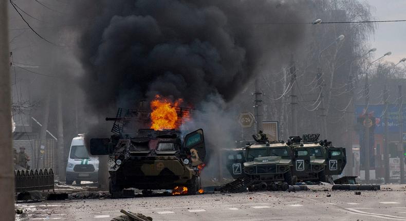 Un véhicule blindé de transport de troupes russe brûle au milieu de véhicules utilitaires légers endommagés et abandonnés après des combats à Kharkiv, en Ukraine, le dimanche 27 février 2022.