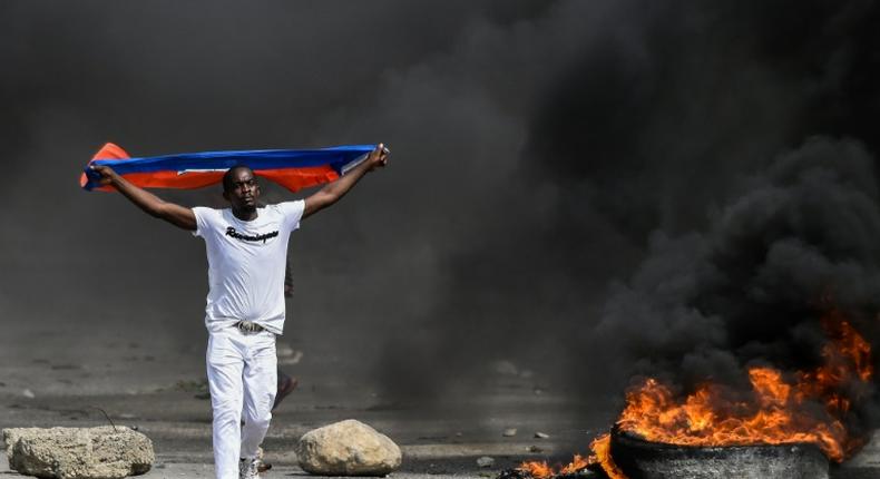 A demonstrator waves a Haitian flag during a protest against President Jovenel Moise on October 4, 2019 in Port-au-Prince