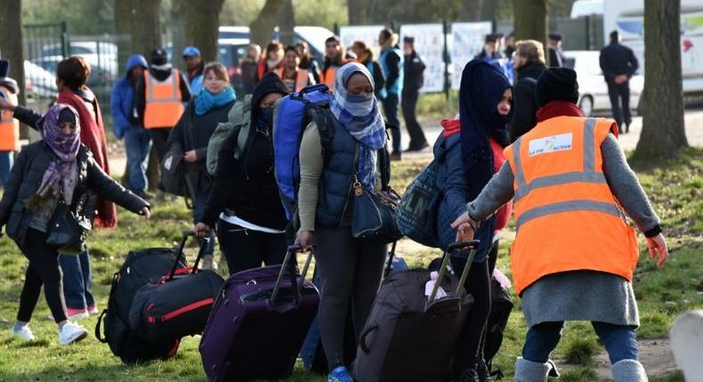 Migrants carry their luggages as they walk to climb into a bus after leaving the Jules Ferry reception centre, next to the recently demolished Jungle migrant camp after a massive operation to clear the settlement, on November 3, 2016, in Calais