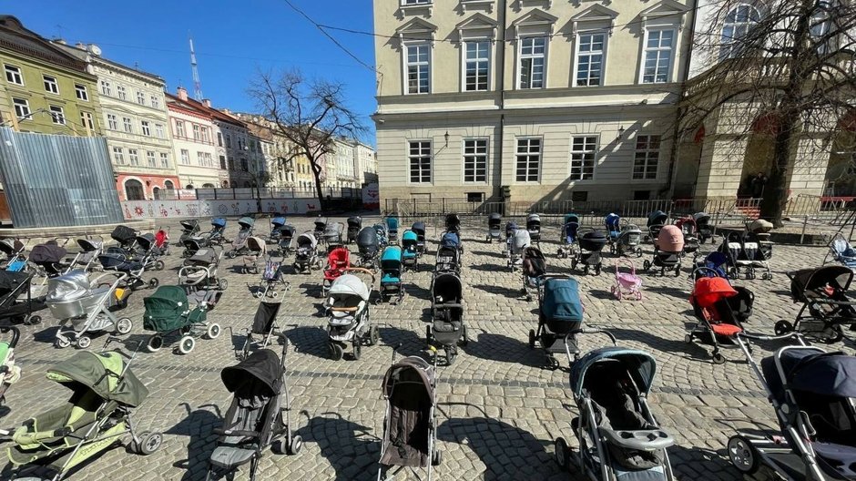 Puste wózki dziecięce na placu we Lwowie symbolizujące zamordowane przez rosyjskich agresorów dzieci