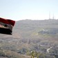 A Syrian national flag flutters as Qasioun mountain is seen in the background from Damascus