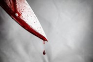 close-up of man holding knife smeared with blood and still dripping.