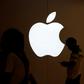 FILE PHOTO: A man looks at the screen of his mobile phone in front of an Apple logo outside its store in Shanghai