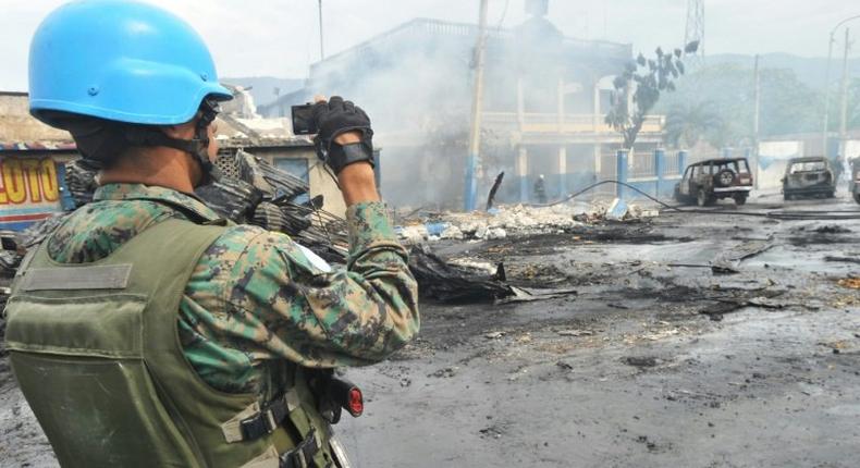 A UN peacekeeper inspects the aftermath of a 2013 blaze that swept through a market in Port-au-Prince