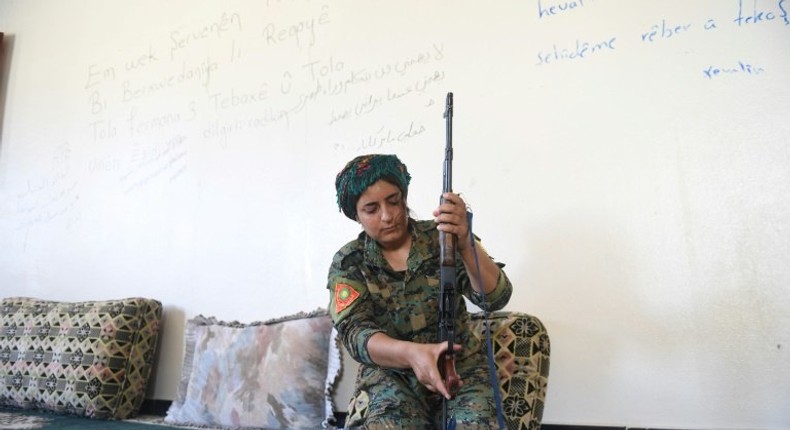 Yazidi fighter Heza prepares her rifle in an abandoned home used as a base on the eastern outskirts of Raqa on July 18, 2017