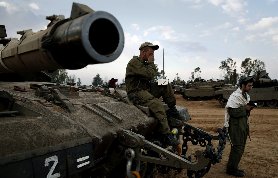 Israeli soldiers pray atop a tank at an Israeli Defence Forces (IDF) staging area by the central Gaza border.