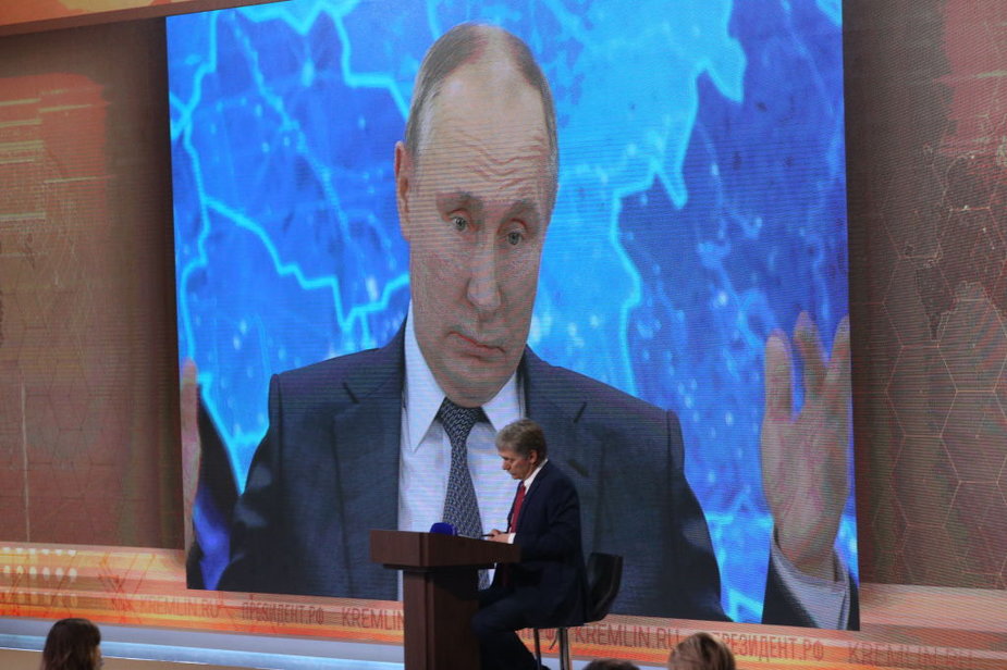 Sekretarz prasowy prezydenta Rosji Dmitrij Pieskow patrzy na Władimira Putina przemawiającego podczas dorocznej konferencji prasowej w grudniu 2020 r.
