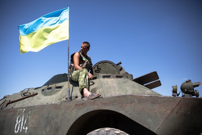 Ukraiński żołnierz siedzi na wojskowym pojeździe w regionie samozwańczej Republiki Doniecka.
