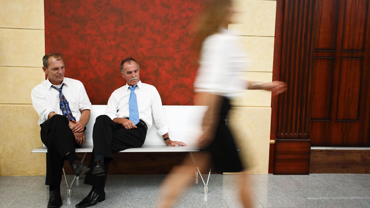 Two businessmen looking at woman's legs