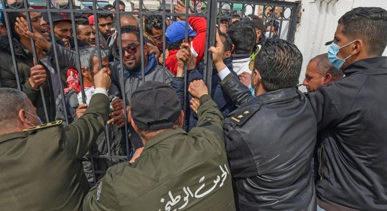 Tunisians angered by a coronavirus lockdown gather outside a government office on the outskirts of the capital