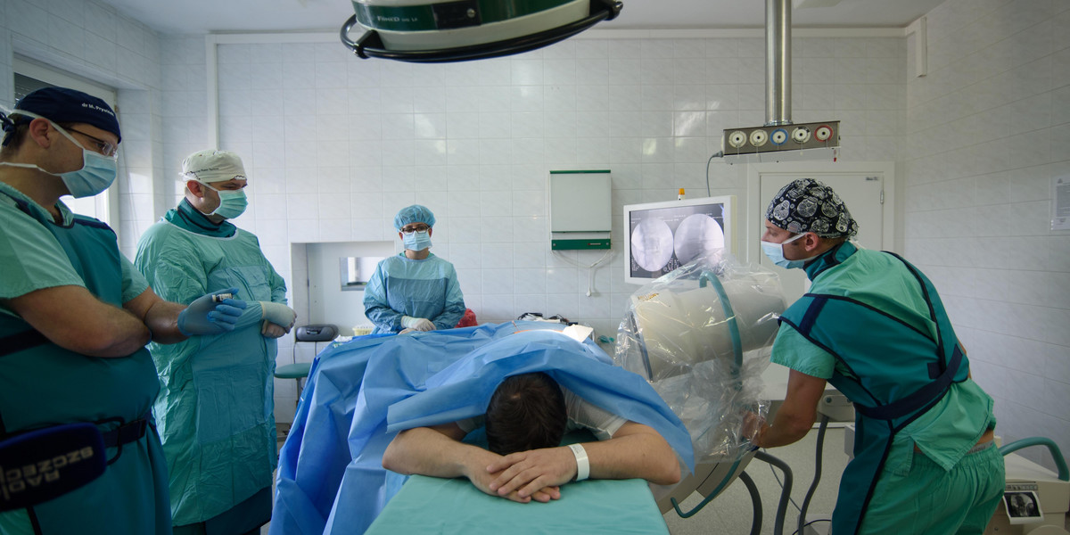 Kontrolując przebieg zabiegu na podglądzie rentgenowskim, neurochirurg wstrzykuje w uszkodzony dysk lędźwiowy mililitr płynnego implantu  