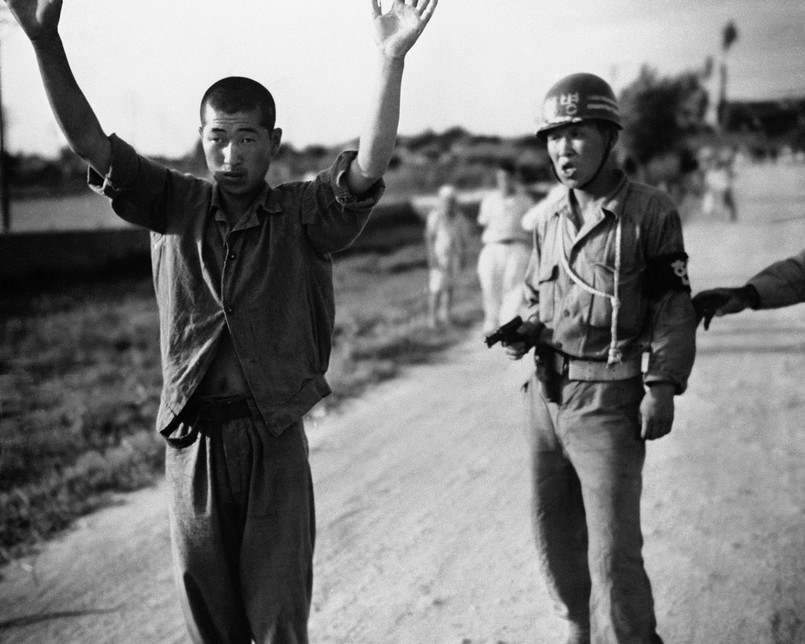 Policjant południowkoreański prowadzi pod bronią północnokoreańskiego jeńca wojennego, 21 lipca 1950 toku