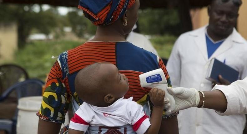 A health worker checks the temperature of a baby entering Mali from Guinea at the border in Kouremale, October 2, 2014.   REUTERS/Joe Penney