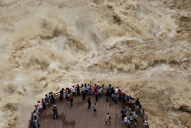 People watch the flooded Jinsha River at a sightseeing platform of Tiger Leaping Gorge, in Diqing