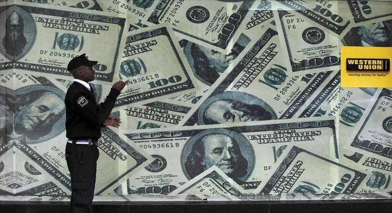 A security guard walks past a montage of old U.S. dollar bills outside a currency exchange bureau ahead of a scheduled State visit by the U.S. President Barack Obama in Kenya's capital Nairobi July 23, 2015.   REUTERS/Thomas Mukoya