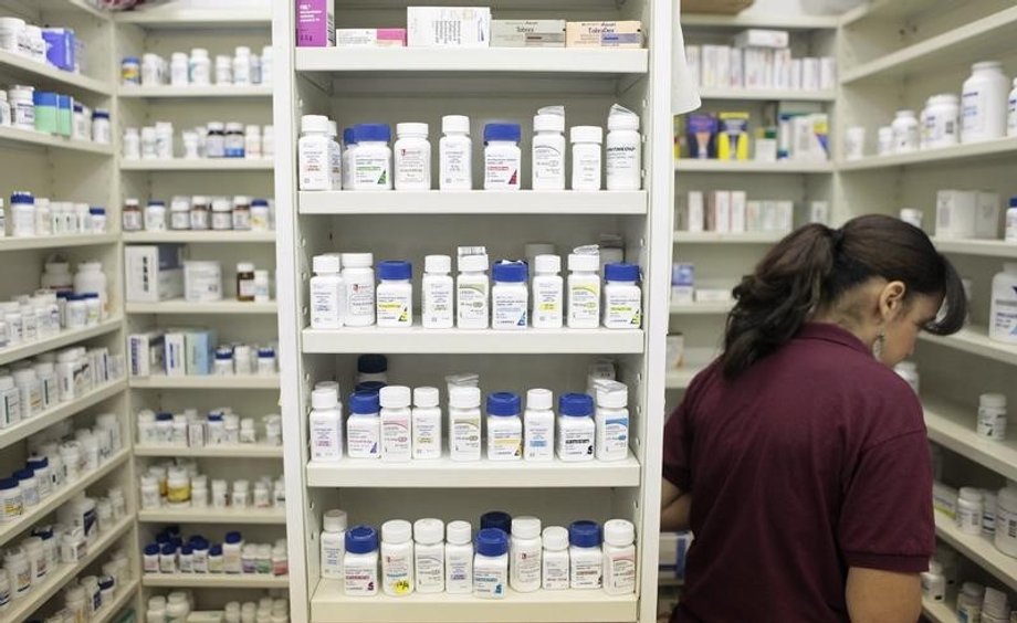 A pharmacy employee looks for medication as she works to fill a prescription.