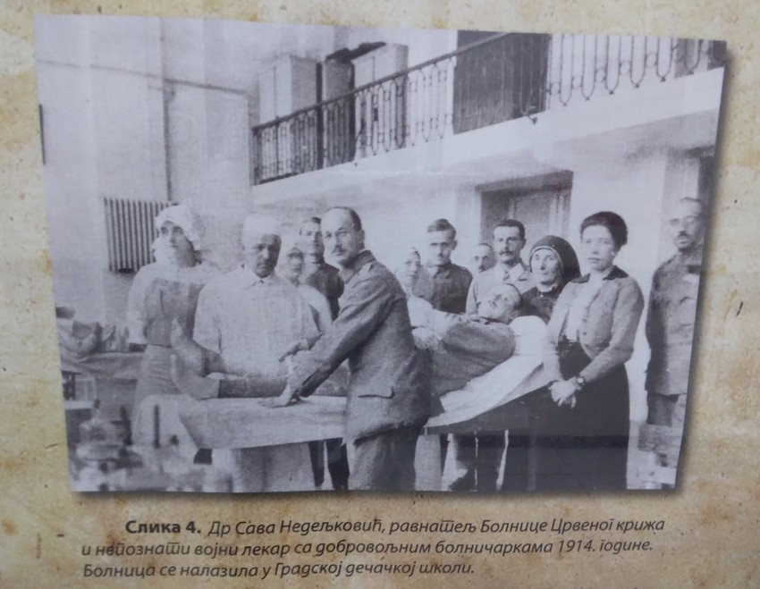 Dr Sava Nedeljković, ravnatelj Bolnice Crvenog križa i nepoznati vojni lekar sa dobrovoljačkim bolničarkama 1914. godine. Bolnica se nalazila u gradskoj dečačkoj školi.