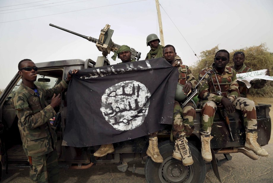 Nigerian soldiers hold up a seized Boko Haram flag after liberating Damasak, Nigeria, March 18, 2015.