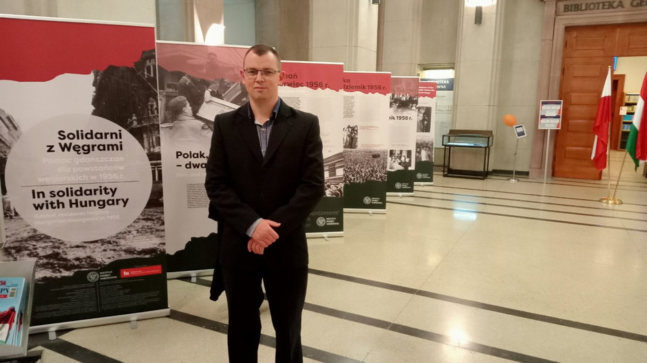 Krzysztof Filip na tle wystawy "Solidarni z Węgrami Pomoc gdańszczan dla powstańców węgierskich w 1956 r."