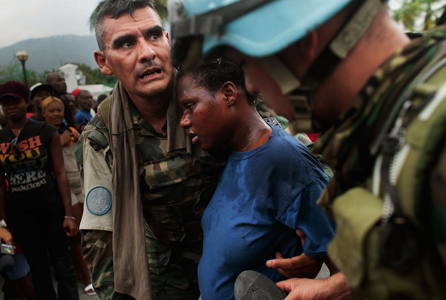 UN peacekeepers tend to a pregnant Haitian woman who lost consciousness in a massive crowd during rice distribution for earthquake-displaced residents. January 25, 2010. Port-au-Prince, Haiti.