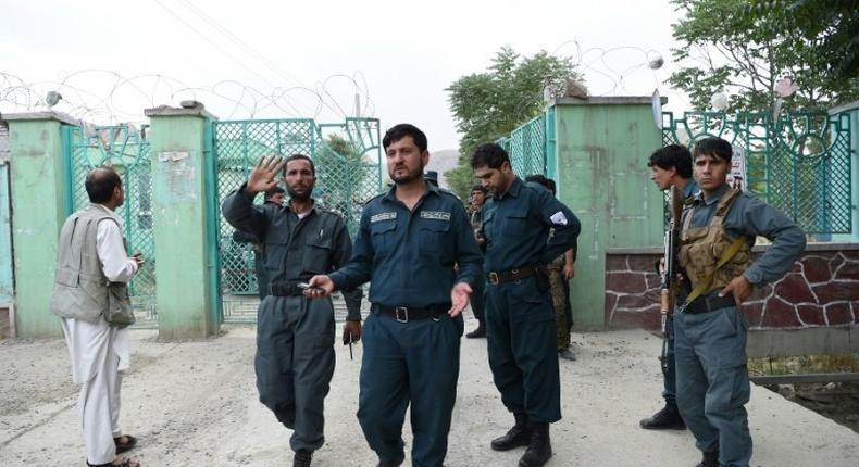 Afghan policemen stand at a gate near the site of a series of explosions that targeted a funeral in Kabul on June 3, 2017